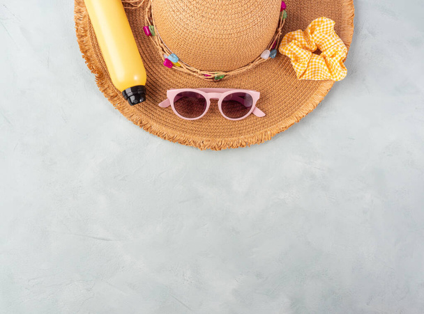 Yaz hanımı hasır şapka, sarı güneş koruması spreyi ve turkuaz taştan arka planda güneş gözlüğü.. - Fotoğraf, Görsel