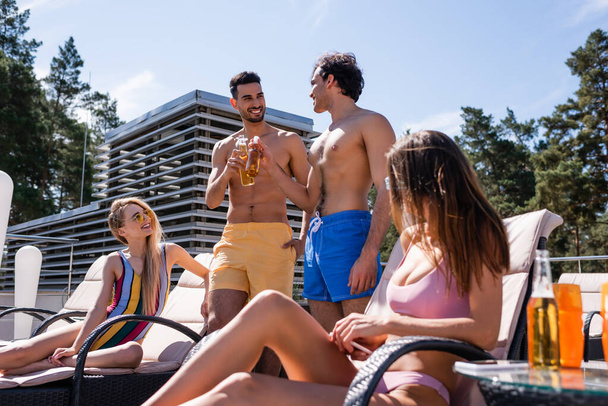Multiehtnic amigos em calções de banho tostando com cerveja ao ar livre  - Foto, Imagem