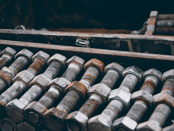 Tornillos oxidados en un pecho de madera, fondo industrial simétrico, tornillos de hierro doblados en una fila, estilo militar retro - Foto, Imagen