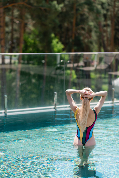 Vista posteriore della giovane donna in costume da bagno in piedi in piscina  - Foto, immagini
