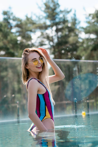 Pretty woman smiling at camera in swimming pool during weekend  - Photo, Image