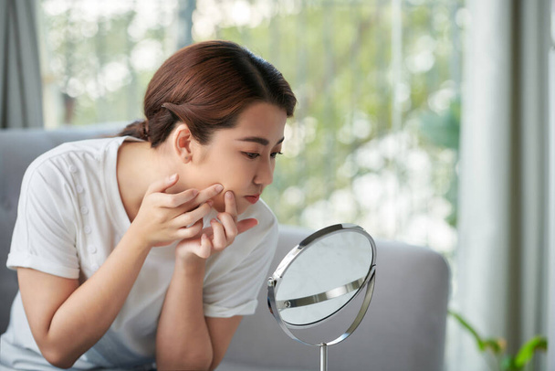 joven mujer exprimir su acné delante del espejo - Foto, Imagen