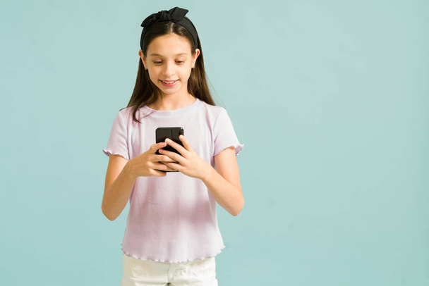 Enjoying my new phone. Cute preteen girl feeling happy while texting and looking at online social media on her smartphone - Fotoğraf, Görsel