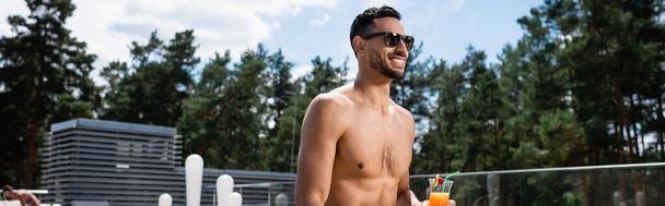 pleased muslim man in sunglasses holding cocktail outdoors - Фото, зображення