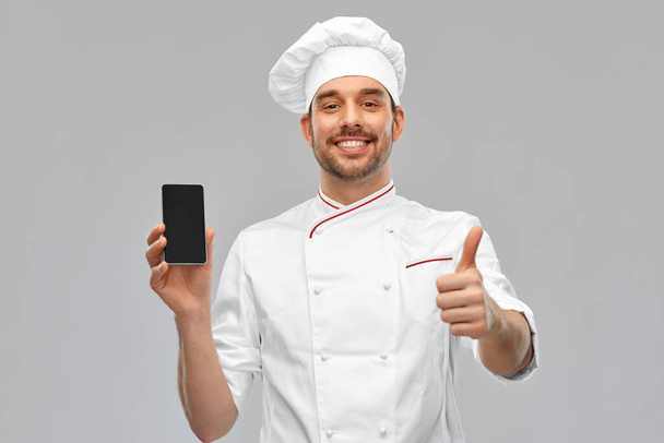 happy chef with smartphone showing and thumbs up - Фото, зображення