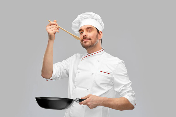happy male chef with frying pan tasting food - Fotografie, Obrázek