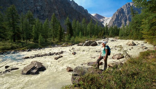 Photo of a tourist girl in the Altai Mountains. In the background is a river flowing from the Bolshoy Aktru glacier. - Fotó, kép