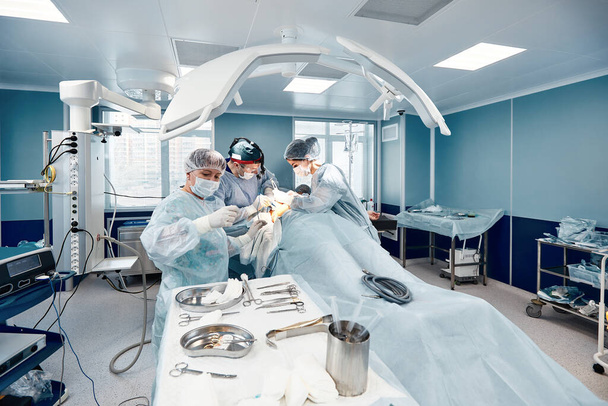Современная операционная, хирурги и врачи, делающие онкологическую операцию, современная медицина, легкий операционный блок. - Фото, изображение
