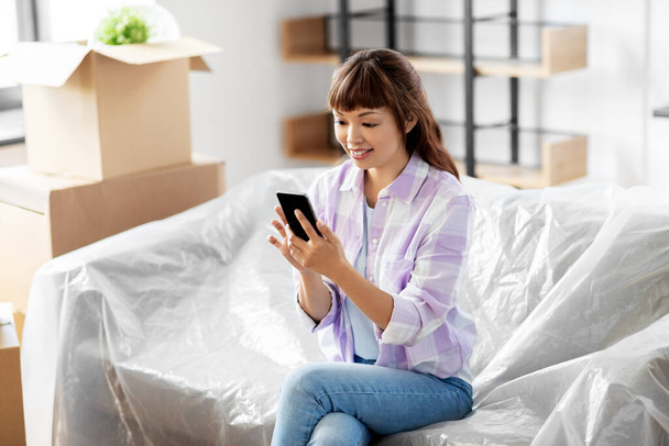 asian woman with smartphone moving into new home - Foto, Imagem