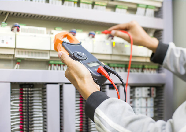 Инженер-электротехнолог регулярно проверяет работу шкафа электроуправления для технического обслуживания. - Фото, изображение