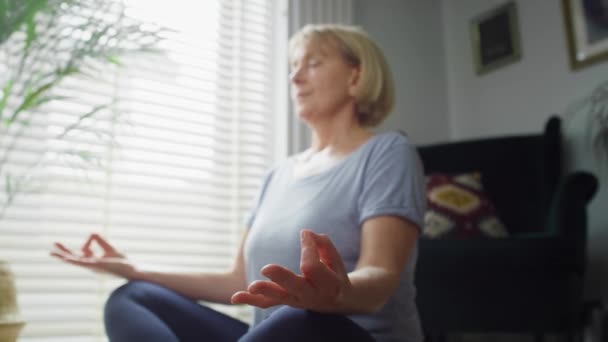 Zblízka video starší ženy meditující doma. Snímek s RED heliovou kamerou v 8K. - Záběry, video