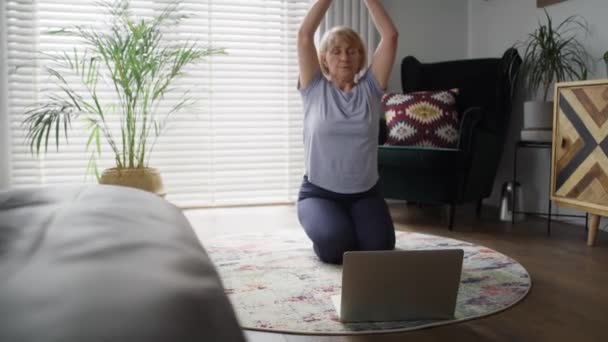 Aktif kıdemli bir kadının egzersiz minderinde meditasyon yapışının videosunu izliyorum. 8K 'da kırmızı helyum kamerayla çekildi. - Video, Çekim