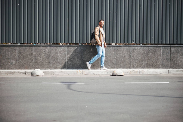 Young international male person going on the sidewalk - Zdjęcie, obraz