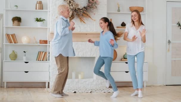 Little adorable daughter laughing jumping between mother and grandmother. Three generations woman old grandma, young woman and child granddaughter feel happy at home. Multigenerational family portrait - Footage, Video
