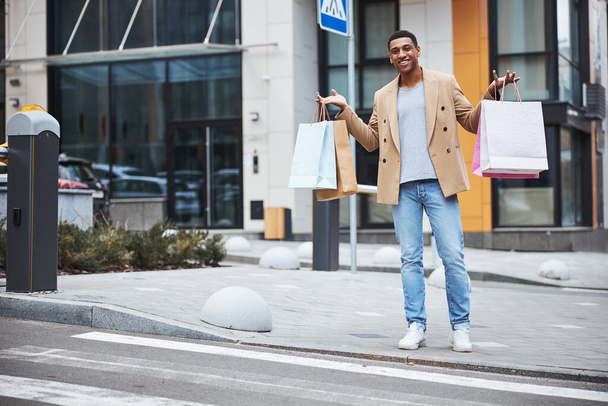 Kind dark-skinned male person demonstrating his purchases - Zdjęcie, obraz
