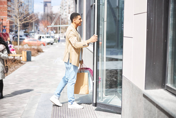 Young handsome man entering building for shopping - 写真・画像