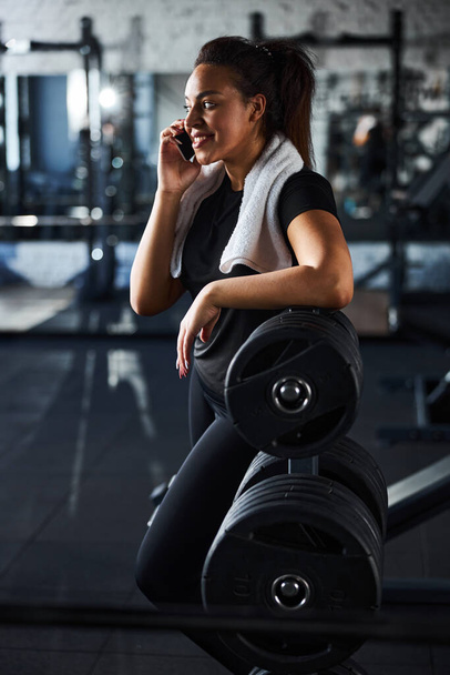 Merry sporty woman making call in fitness studio - Zdjęcie, obraz