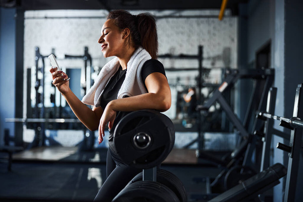 Smiling female sport instructor with smartphone in gym - Foto, Imagen