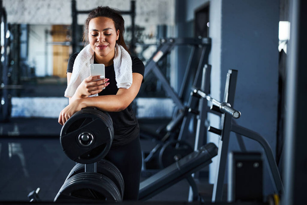 Smiling beautiful woman with cell phone in gym - Foto, immagini