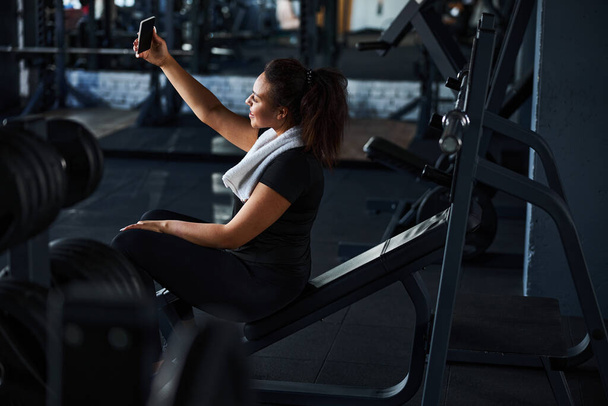 Jolly young woman taking photo in gym - Foto, Imagen