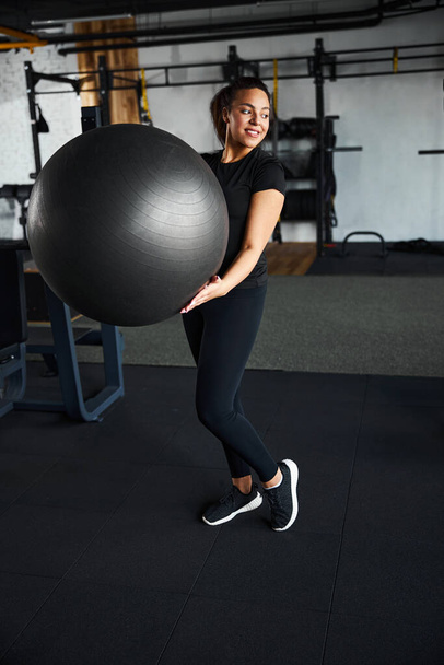 Joyful young woman using equipment in gym - Foto, Imagem