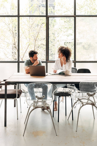 Young multiracial people interacting in bright co working loft office with big window. Coworkers concept. Vertical image. Business meeting concept. Startup concept. Copy space. - Foto, Imagen