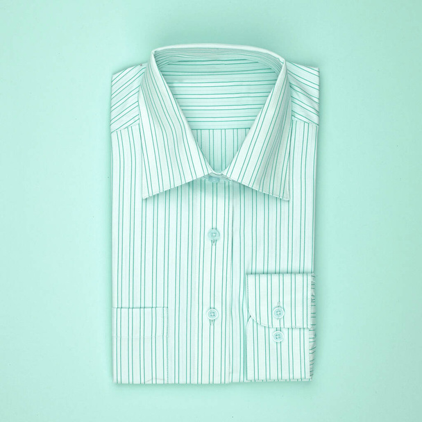 Ein neues Hemd im Schaufenster oder im Lager. Unisex cyanblaue, weiße, gestreifte Kleidung. Verkauf, Rabatte, Aktionskonzept. - Foto, Bild