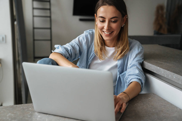 Happy beautiful young woman using laptop computer at home - Φωτογραφία, εικόνα