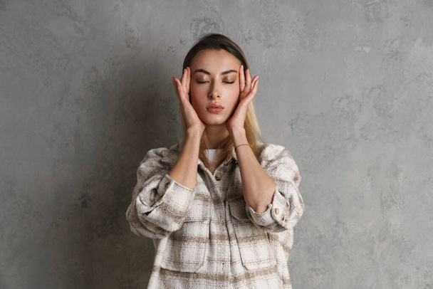 Upset displeased young woman suffering from a headache isolated over gray background - Foto, Imagem