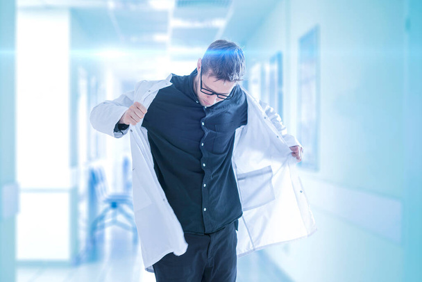 mies lääkäri laittaa lääkärin puku sairaalassa, klinikan nuori asiantuntija - Valokuva, kuva