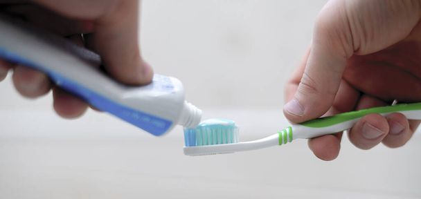 osoba stisknout zubní pastu na kartáček v koupelně - Fotografie, Obrázek