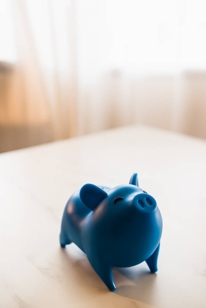 Голубая голубая банковская коробка, поставленная на стол с мягким светом и пространством для копирования. Экономия денег. - Фото, изображение