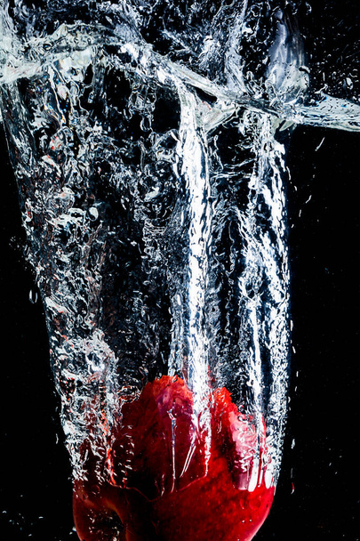 red apple thrown into water with splash and black background. - Φωτογραφία, εικόνα