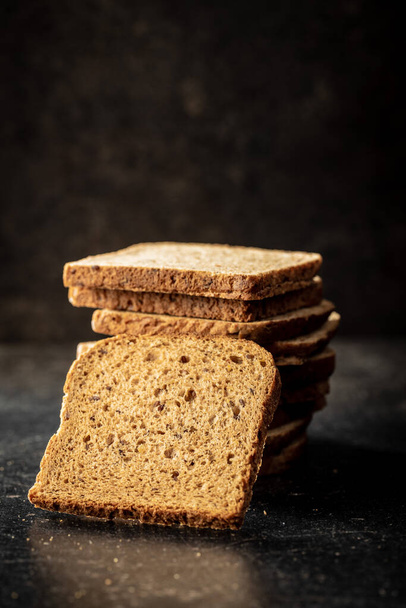 Sliced wholegrain bread on black table. - Foto, Bild