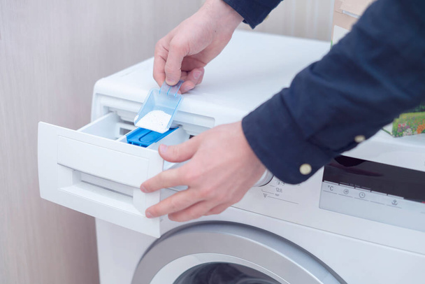 una persona carica il detergente in polvere in lavatrice - Foto, immagini