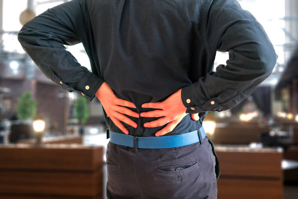 ένα άτομο που αισθάνεται τον πόνο στην πλάτη, άγχος υπερκόπωση πρόβλημα ασθένειας - Φωτογραφία, εικόνα