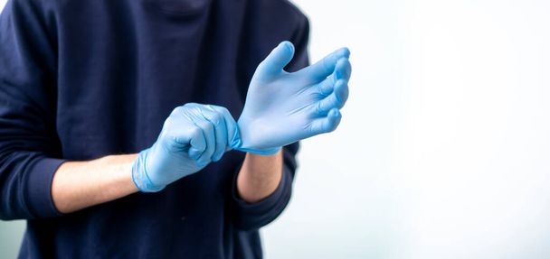 uma pessoa de perto tentar colocar luvas de proteção nas mãos para proteger da epidemia de coronavidus - Foto, Imagem