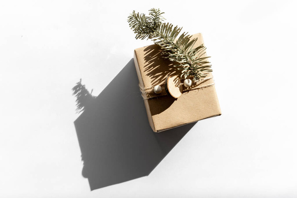 Gift in craft paper on a white with shadow isolated, christmas and zero waste, eco friendly packaging. Ecological Christmas holiday concept, eco decor - 写真・画像