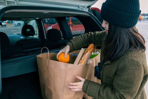 mujer puso bolsas con productos en el maletero del coche después de la tienda de comestibles - Foto, Imagen