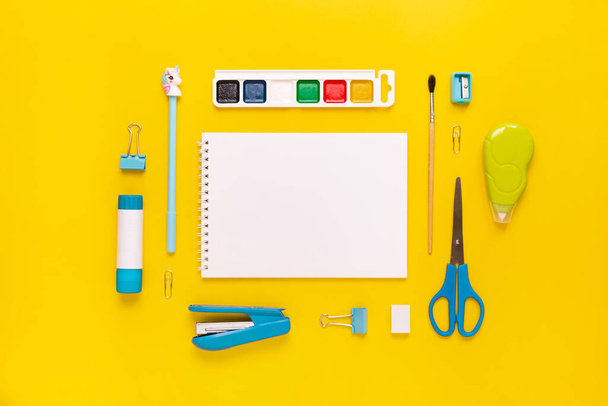 Top view of modern white, blue, yellow office desktop with school supplies and stationery on table around empty space for text. Back to school concept flat lay with mockup - Photo, Image