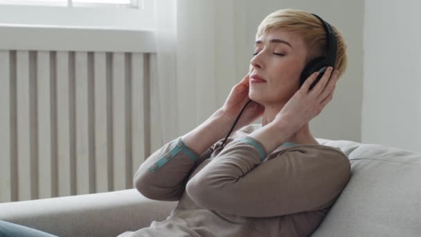 Спокійна молода доросла жінка, яка розслабляється на комфортабельних диванних очах закритих навушниках, насолоджується послухати улюблену прохолодну музику аудіокнигу, медитувати спокійний настрій, розслаблятися, не відчуваючи стресу вдома концепції
 - Кадри, відео