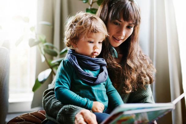 Ujęcie młodej kobiety czytającej synowi w domu. - Zdjęcie, obraz