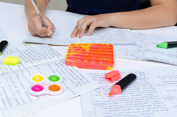 Une adolescente étudie avec pop it et simple fossette anti stress jouets couchés sur la table. - Photo, image
