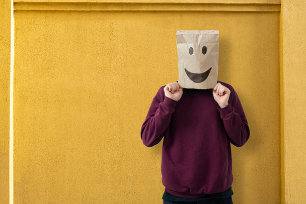 ένα άτομο με χάρτινη σακούλα στο κεφάλι με ένα χαμόγελο, χαρούμενη ιδέα επιτυχίας - Φωτογραφία, εικόνα