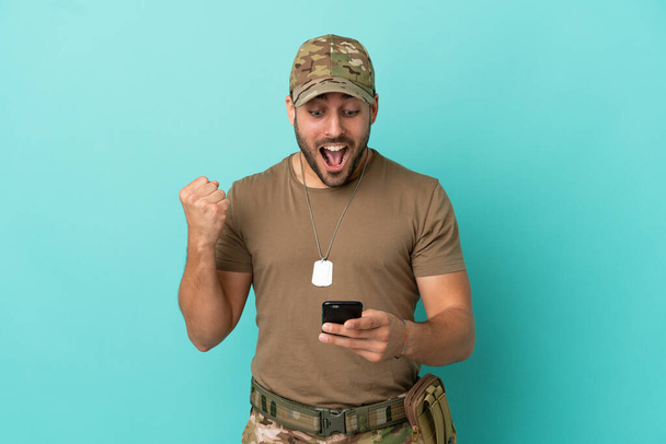 Military with dog tag over isolated on blue background surprised and sending a message - Foto, Imagem