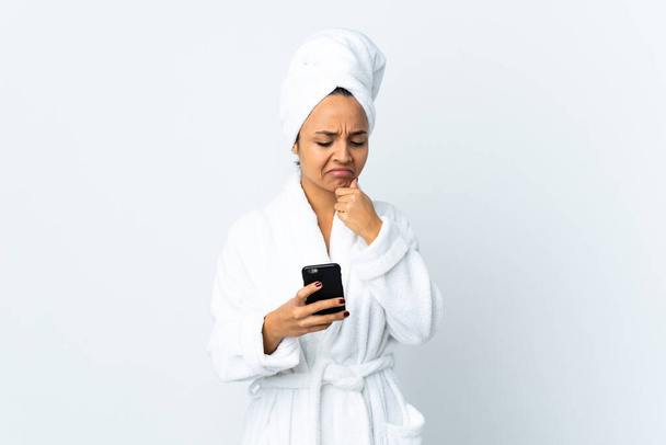 Mujer joven en albornoz sobre fondo blanco aislado pensando y enviando un mensaje - Foto, Imagen