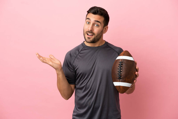 Young caucasian man playing rugby isolated on pink background extending hands to the side for inviting to come - Foto, Imagem