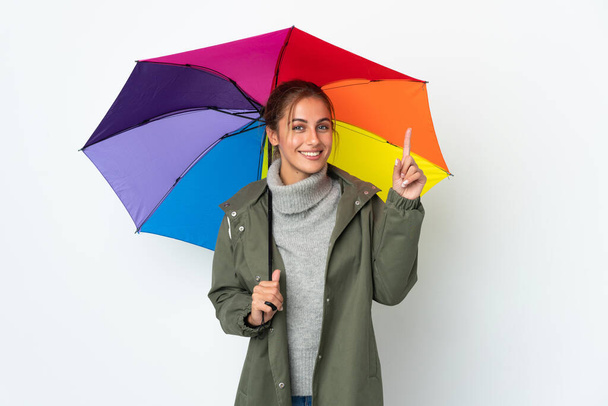 Молодая женщина с зонтиком на белом фоне указывает на отличную идею - Фото, изображение