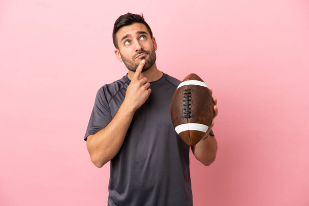 Young caucasian man playing rugby isolated on pink background having doubts while looking up - Foto, Bild