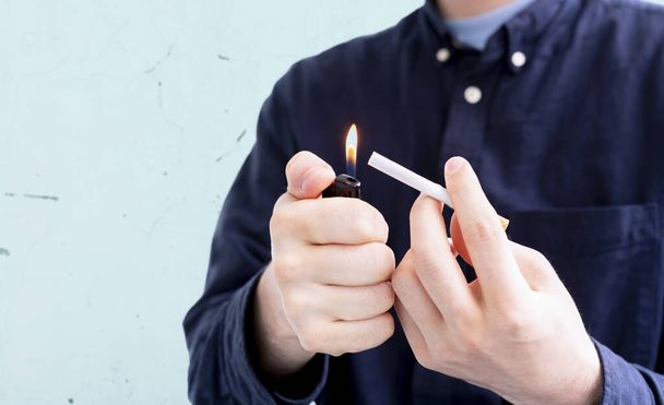 una persona che tiene una fiamma accendino scintilla e una sigaretta, fumare male habbit - Foto, immagini